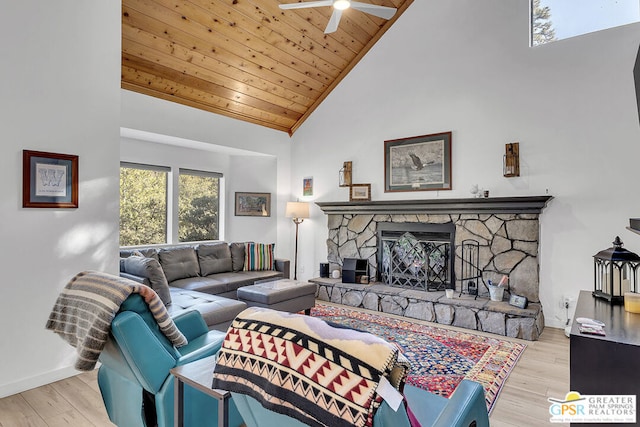 living room with wooden ceiling, light hardwood / wood-style flooring, a stone fireplace, and high vaulted ceiling