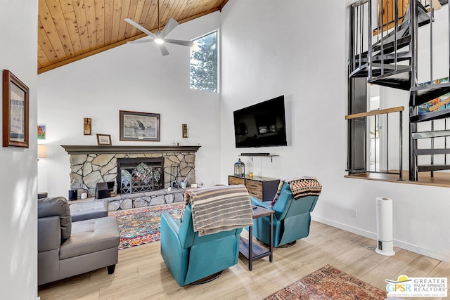 living room with ceiling fan, light wood-type flooring, a stone fireplace, high vaulted ceiling, and wooden ceiling