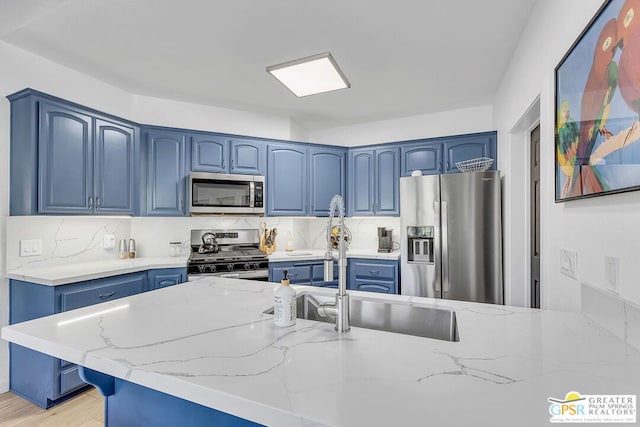 kitchen featuring blue cabinetry, stainless steel appliances, and light stone counters