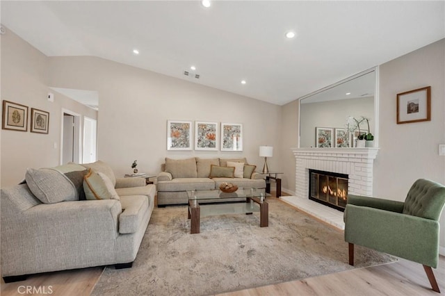 living room with light hardwood / wood-style floors, lofted ceiling, and a fireplace