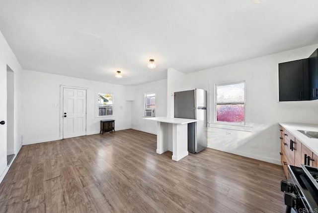 kitchen featuring hardwood / wood-style flooring, light brown cabinetry, stainless steel fridge, and a breakfast bar area