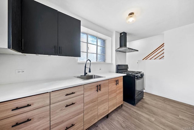 kitchen with wall chimney exhaust hood, sink, light hardwood / wood-style flooring, and black gas range oven