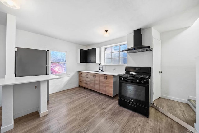 kitchen featuring a wealth of natural light, wall chimney exhaust hood, a kitchen bar, sink, and black range with gas stovetop