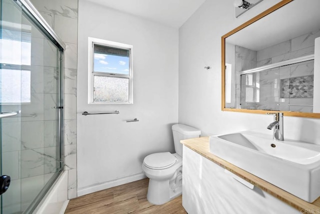 full bathroom with vanity, toilet, bath / shower combo with glass door, and wood-type flooring