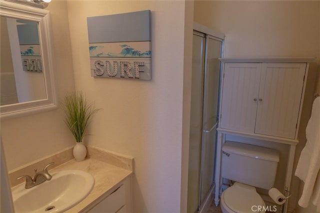 bathroom with a shower with door, toilet, and vanity