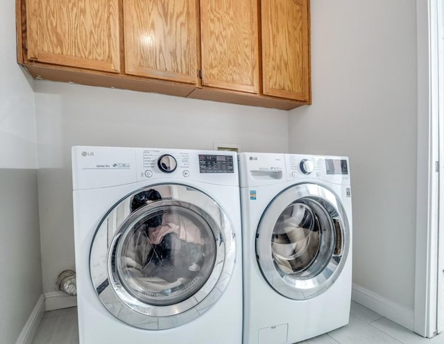 laundry area featuring light tile patterned flooring, washer and dryer, and cabinets