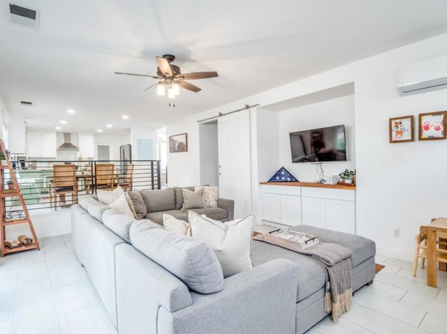 living room featuring ceiling fan, a barn door, and an AC wall unit