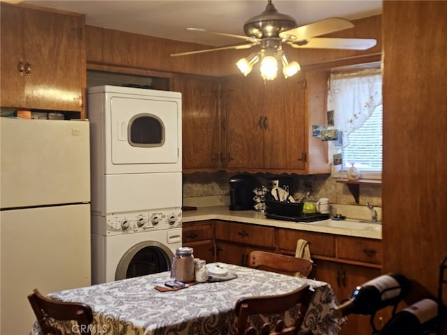 kitchen featuring ceiling fan, decorative backsplash, stacked washing maching and dryer, and white fridge