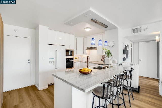 kitchen featuring light hardwood / wood-style floors, black appliances, pendant lighting, white cabinets, and sink