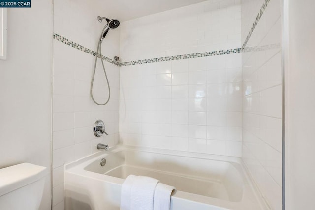 bathroom featuring tiled shower / bath combo and toilet