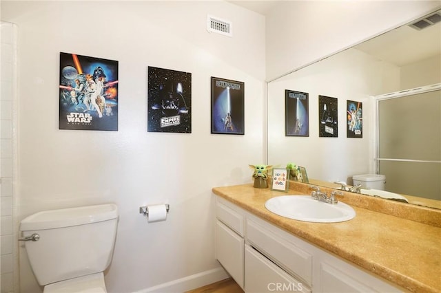 bathroom with toilet, vanity, and an enclosed shower