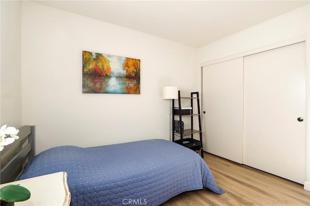 bedroom with light hardwood / wood-style floors and a closet