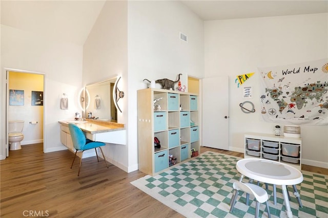 rec room with high vaulted ceiling and wood-type flooring