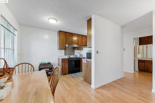 kitchen with a textured ceiling, black microwave, light hardwood / wood-style floors, and range with electric cooktop