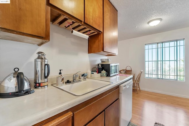 kitchen featuring a textured ceiling, dishwasher, light hardwood / wood-style flooring, and sink