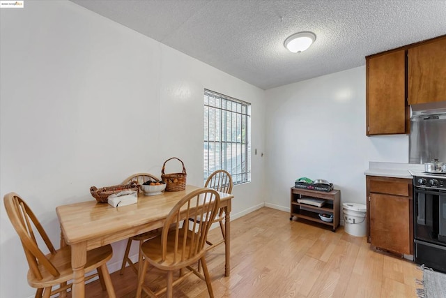 dining area with a textured ceiling and light hardwood / wood-style flooring