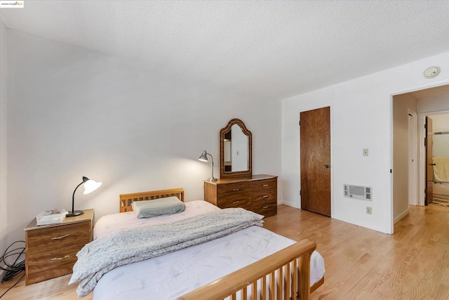 bedroom with a textured ceiling and light wood-type flooring