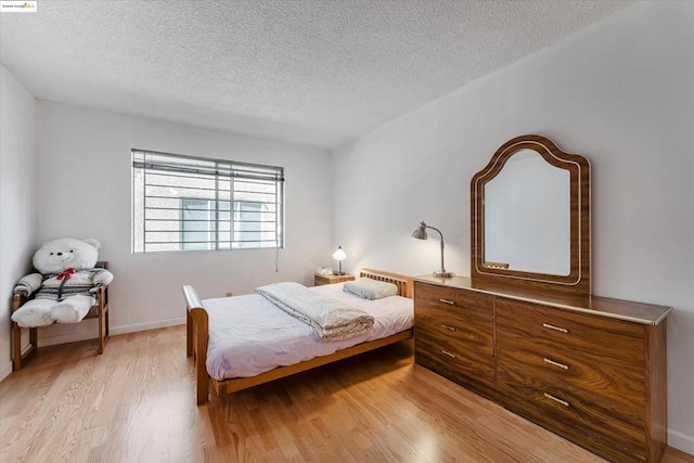 bedroom featuring a textured ceiling and light hardwood / wood-style flooring