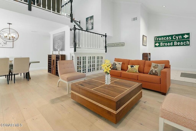 living room featuring a high ceiling, a chandelier, and light hardwood / wood-style flooring