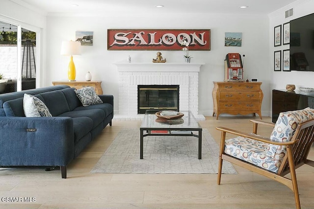 living room with a brick fireplace, crown molding, and light hardwood / wood-style flooring