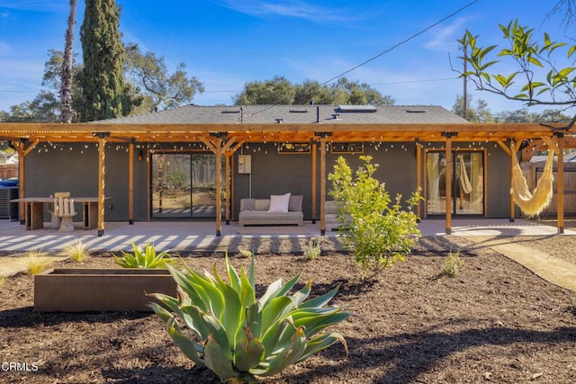 back of property featuring stucco siding, a patio, an outdoor hangout area, and a pergola