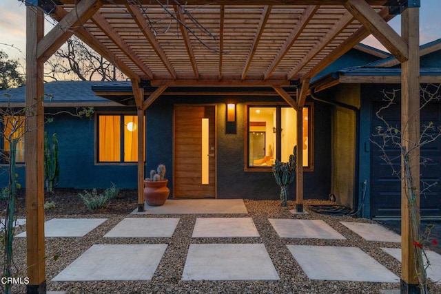 property entrance featuring a pergola, roof with shingles, and stucco siding