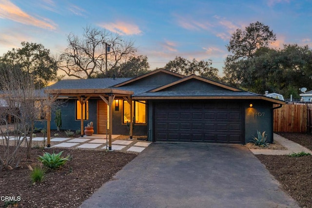 view of front of property with driveway, an attached garage, and fence