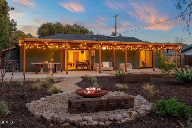 back of property at dusk with central air condition unit, a patio area, fence, and stucco siding