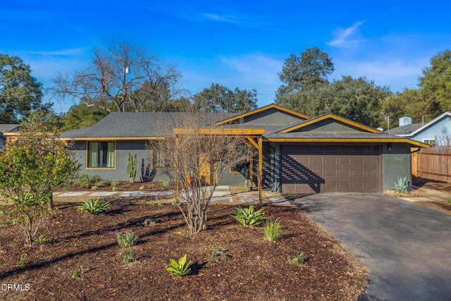 ranch-style house featuring aphalt driveway, stucco siding, an attached garage, and fence