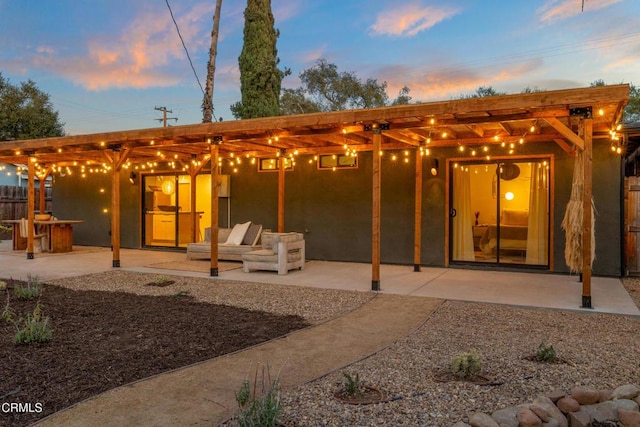 back of property at dusk featuring stucco siding and a patio