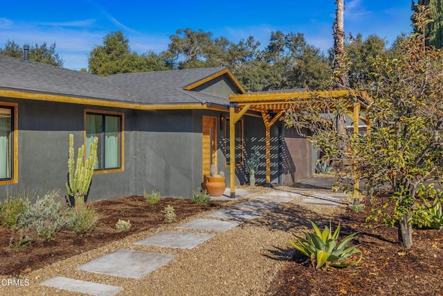 view of front facade with roof with shingles and stucco siding