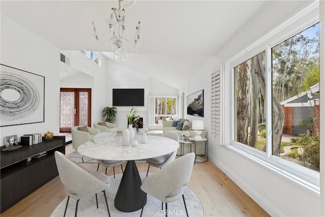 dining room featuring light hardwood / wood-style flooring, a notable chandelier, and vaulted ceiling