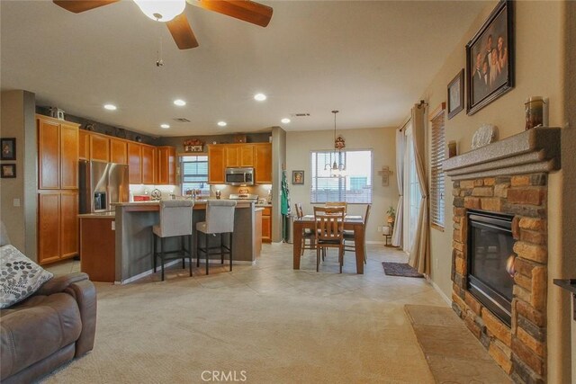 kitchen featuring decorative light fixtures, a center island, light carpet, a kitchen breakfast bar, and stainless steel appliances