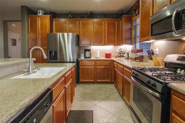 kitchen with sink, light tile patterned floors, appliances with stainless steel finishes, light stone countertops, and backsplash