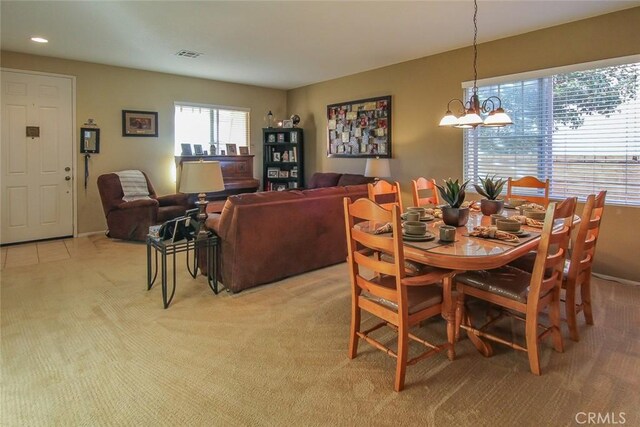 dining room with light colored carpet and a chandelier