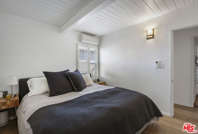 bedroom featuring wood-type flooring, beamed ceiling, and a wall mounted air conditioner