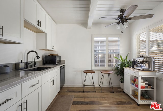 kitchen with stainless steel dishwasher, dark hardwood / wood-style flooring, beamed ceiling, and white cabinetry