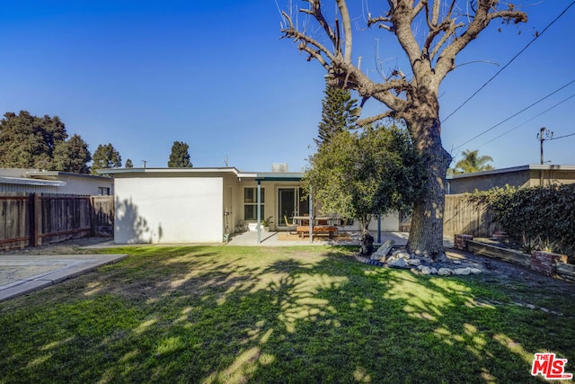 back of house featuring a lawn and a patio