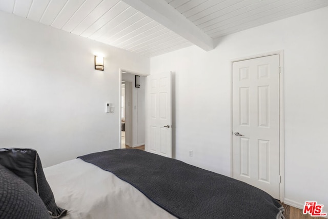 bedroom featuring hardwood / wood-style flooring and beam ceiling