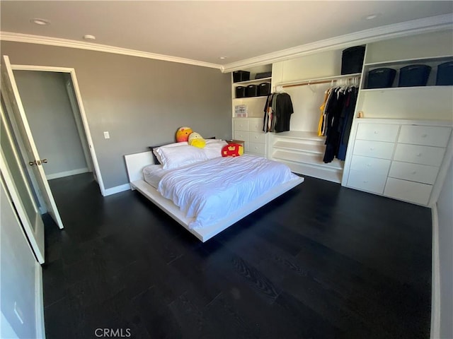 bedroom with dark hardwood / wood-style flooring, crown molding, and a closet