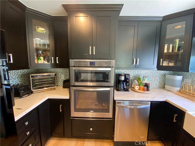 kitchen with tasteful backsplash, light stone countertops, and appliances with stainless steel finishes