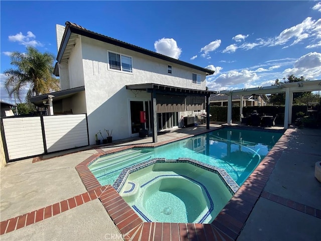 back of property featuring a pool with hot tub, a pergola, and a patio