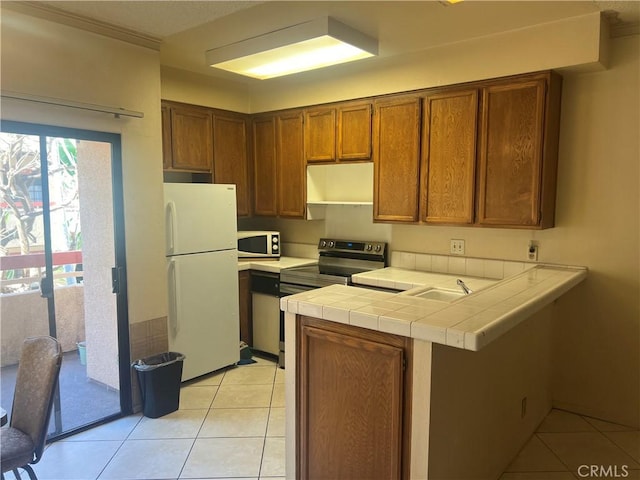 kitchen featuring tile countertops, white fridge, kitchen peninsula, electric range, and light tile patterned floors