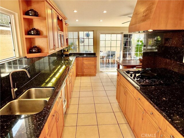 kitchen with light tile patterned floors, sink, dark stone countertops, backsplash, and gas stovetop