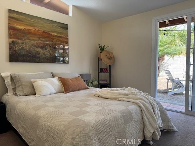 carpeted bedroom with vaulted ceiling and access to outside