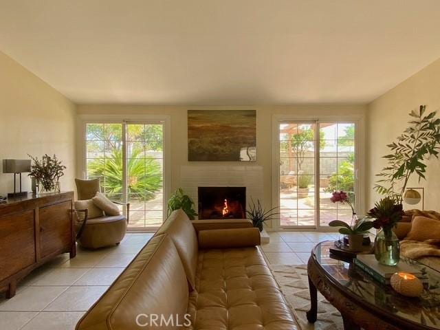 interior space with light tile patterned floors and a warm lit fireplace