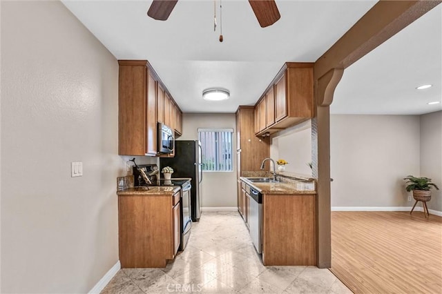 kitchen featuring dark stone countertops, sink, stainless steel appliances, and ceiling fan