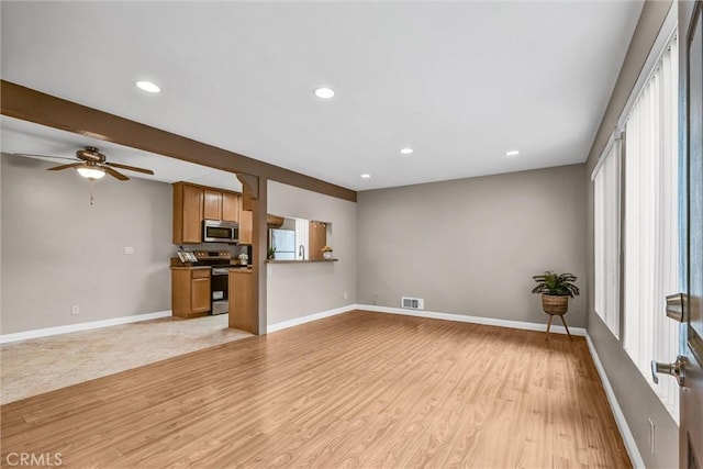 unfurnished living room featuring beamed ceiling, ceiling fan, and light wood-type flooring