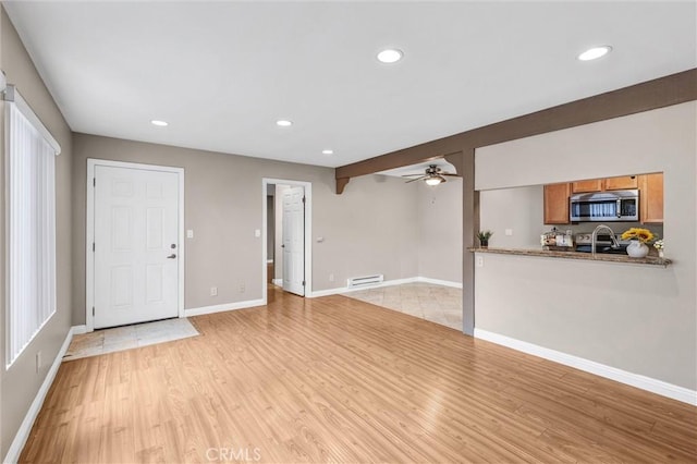 unfurnished living room featuring ceiling fan and light hardwood / wood-style floors