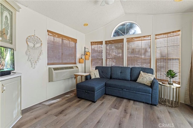 living room featuring a wall unit AC, plenty of natural light, lofted ceiling, and wood-type flooring